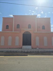 an orange and white building with a black door at شقق عبدالله in Al-ʿUla