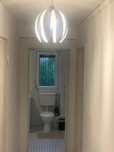 a bathroom with a toilet and a window and a chandelier at Chambre à Hoenheim à 10 min de Strasbourg une chambre cosy in Hoenheim