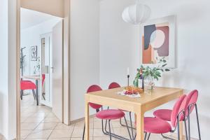a dining room with a wooden table and pink chairs at NEW-Rosalia-Stilvoll wohnen, zentral erleben in Kaiserslautern