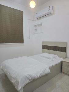 a bedroom with a white bed and a window at شقق عبدالله in Al-ʿUla