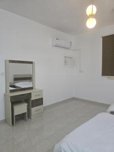 a bedroom with a bed and a vanity with a mirror at شقق عبدالله in AlUla