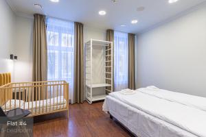 a bedroom with a bed and a crib and windows at Dandelion Apartments Bruņinieku in Rīga