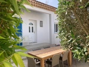 a wooden table and chairs in front of a house at Belle villa spacieuse avec piscine privée, semi climatisée- 10 couchages, wifi, proche canal du midi et à 4 km de la mer LXPIN7 in Portiragnes