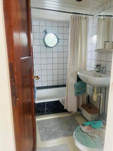 Un baño con bañera, lavabo y espejo. en The Island Houseboat, en Ámsterdam