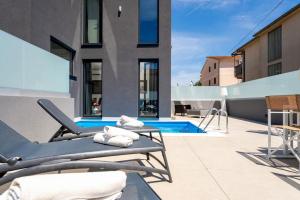 un patio con sedie a sdraio e una piscina di Casa Brave by Briskva a Funtana