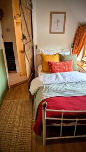 a bedroom with a bed with red and yellow pillows at Parsons Cottage - A rural retreat South Norfolk in Rockland Saint Mary
