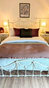 a large bed in a bedroom with two lamps at Parsons Cottage - A rural retreat South Norfolk in Rockland Saint Mary