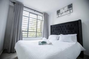 a bedroom with a white bed with a large window at 1 bedroom cosy apartment in Nairobi, Kitsuru in Nairobi