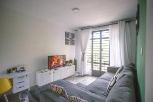 a living room with a couch and a large window at 1 bedroom cosy apartment in Nairobi, Kitsuru in Nairobi