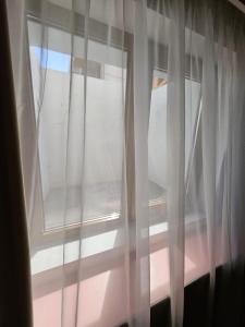 a window with white curtains in a room at Casa Raduly - Apartament Demisol in Sibiu