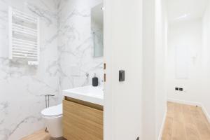 a white bathroom with a toilet and a sink at Margot in Beausoleil
