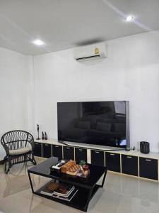 a living room with a table and a large tv at Happy Villa in Choengtalay in Laguna Phuket