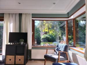 a living room with a tv and a large window at Het Vijverhuisje - Holiday only in Doornspijk