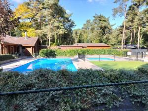 a swimming pool in a yard with a house at Het Vijverhuisje - Holiday only in Doornspijk