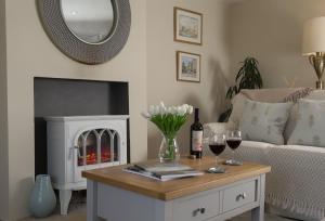 a living room with a fireplace and a table with wine glasses at Spring Cottage in Painswick