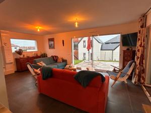 ein Wohnzimmer mit einem roten Sofa und Stühlen in der Unterkunft En famille ou amis avec la mer in Équihen-Plage
