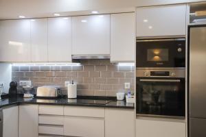 a kitchen with white cabinets and black counter tops at Villa ELTAEL - Miguel House - Warm Pool until 1 November - Facilities for disabled guests in Manta Rota