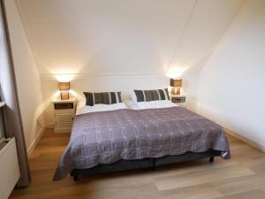 a bedroom with a bed with two night stands and two lamps at Buitenplaats 108 in Callantsoog