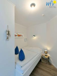 a bedroom with a bed with blue pillows on it at Bootshaus in den Duenen - 5 - "Ferienwohnung Duenengefluester" in Wangerooge