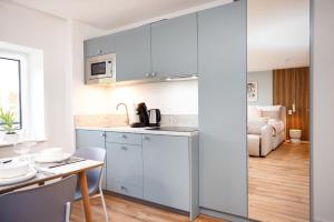 a kitchen with white cabinets and a table with chairs at DWELLSTAY - City Apartments Fulda in Fulda