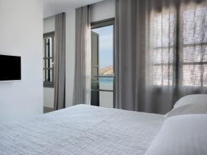 a bedroom with a bed and a large window at Acteon Hotel in Ios Chora