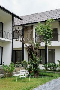 a group of chairs and a tree in front of a building at Shanti-Retreat Hotel in Pua