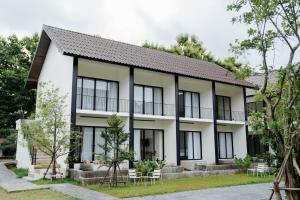 a white building with black windows and trees at Shanti-Retreat Hotel in Pua