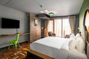 a hotel room with a bed and a flat screen tv at MeStyle Museum Hotel in Bangkok