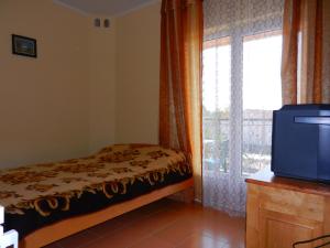 een slaapkamer met een bed, een raam en een tv bij Guest house Villa Leonardo in Herceg-Novi
