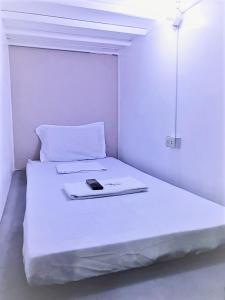un letto bianco con un telefono cellulare sopra di RDC - Mariveles Transient Capsule a Manila