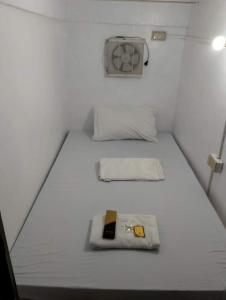 una piccola camera da letto con due letti e un ventilatore di RDC - Mariveles Transient Capsule a Manila