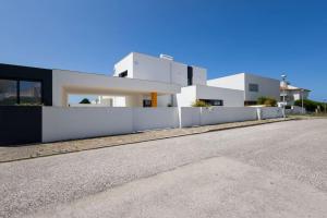 a white house with a fence next to a street at Villa Pessegueiros in Ericeira