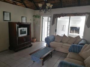 a living room with a couch and a tv at Arniston Cottage in Arniston