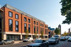 a busy city street with cars parked in front of a brick building at Bradbury Place in Belfast
