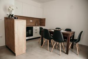 a kitchen with a wooden table and black chairs at Apartman Krznarić in Županja
