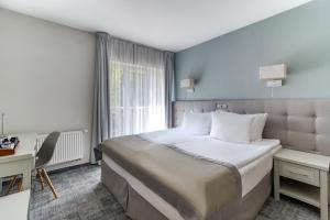 a bedroom with a bed and a desk and a window at Hotel Aqua Sopot - Destigo Hotels in Sopot