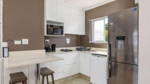 a kitchen with white cabinets and a stainless steel refrigerator at Bay Lodge 29 in Ballito