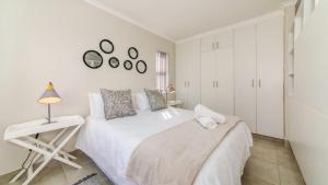 a white bedroom with a bed and a table at Bay Lodge 29 in Ballito