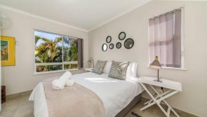 a white bedroom with a white bed and a window at Bay Lodge 29 in Ballito +7 photos