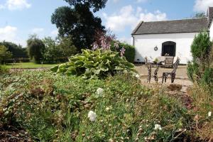 a garden with a bench in front of a white building at WestLaigh Central Scotland with outdoor BBQ Hut, pets welcome in Strathaven