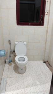 a bathroom with a toilet with a window and a tv at Holiday Home, 3 Bedroom in Sungguminasa