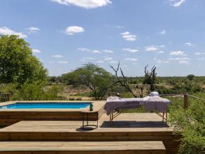 a table and a chair on a deck next to a pool at Simbavati Mvubu Cottage in Timbavati Game Reserve