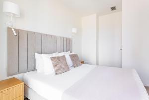 une chambre blanche avec un grand lit blanc avec des oreillers dans l'établissement Intempo by Holuxe - 045 - 4th floor, à Benidorm