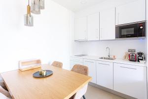 une cuisine avec des armoires blanches et une table en bois dans l'établissement Intempo by Holuxe - 045 - 4th floor, à Benidorm