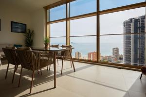 a dining room with a table and chairs and large windows at Intempo by Holuxe - 096 - 9th floor in Benidorm