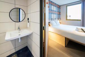 a bathroom with a sink and a bed with a mirror at easyHotel Marseille Euromed in Marseille +25 photos