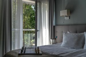 a bed with a chess board on it in front of a window at Hotel Aqua Sopot - Destigo Hotels in Sopot