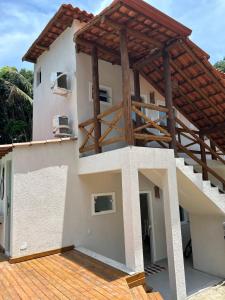 a house with a porch and a wooden deck at Su House Suíte Arraial dAjuda in Porto Seguro