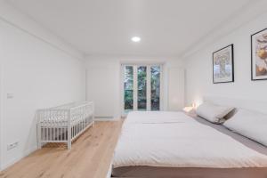 1 dormitorio blanco con 2 camas y 1 cuna en Wohnung in Toplage in Düsseldorf-Oberkassel, en Düsseldorf