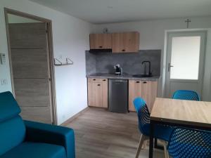 a kitchen with a table and blue chairs in a room at Charmant appartement au calme in Gilhoc sur Ormeze
